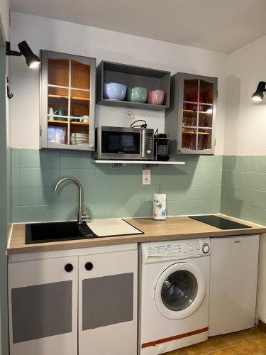 a kitchen with a sink and a washing machine at Studio Cosy près du Lac in Sainte-Croix-de-Verdon