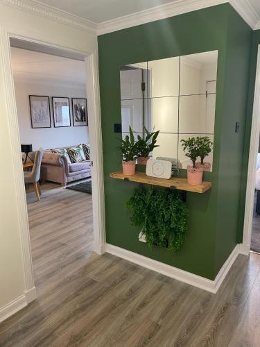 a living room with a green wall with plants on a shelf at The Marine - Balcony - Beach View - Coorie Doon Stays in Ayr