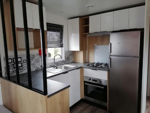 a small kitchen with a refrigerator and a sink at Bora Bora 6/8 personnes in Litteau