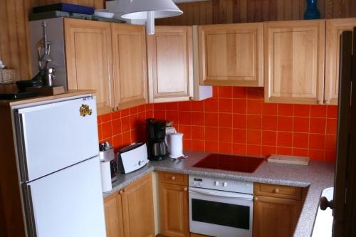 La cuisine est équipée d'un réfrigérateur blanc et de placards en bois. dans l'établissement Belles vacances dans belle région, à Saint-Chaffrey