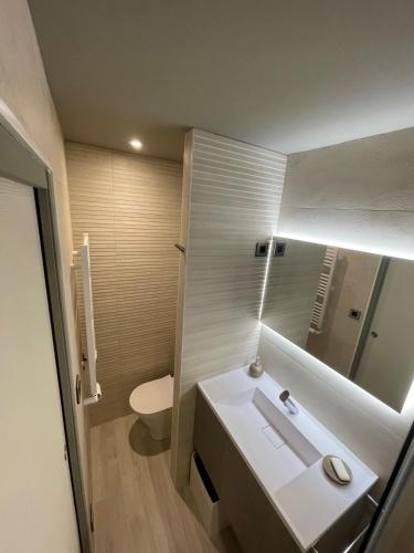 une salle de bain avec un lavabo, des toilettes et un miroir dans l'établissement Le P'tit Carnon, à Mauguio