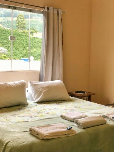 a bed with two towels on it with a window at Estalagem e Restaurante Cantinho Bistrô in Alto Caparao