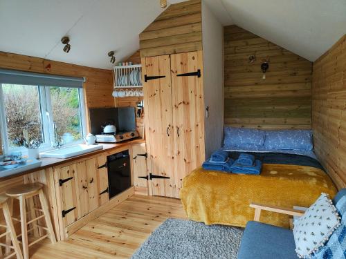 1 dormitorio pequeño con 1 cama y cocina en Dryw bach glamping hut, en Llandeilo