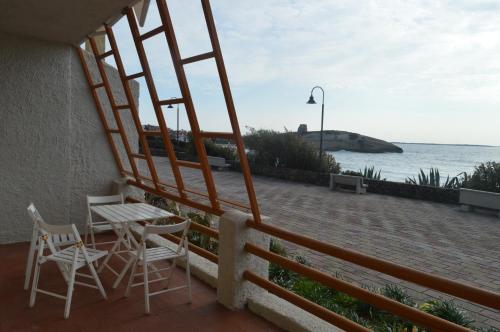 balcón con sillas, mesa y vistas al océano en Casa del Giglio, en S'Archittu