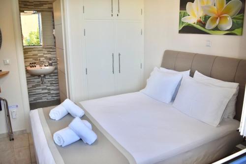 ein Schlafzimmer mit einem Bett mit weißen Kissen und einem Waschbecken in der Unterkunft Lovely Rooms Finikounda in Finikounda