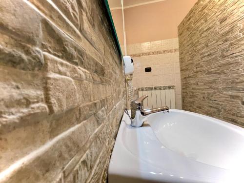 a bathroom with a white tub and a stone wall at Il Sogno nel Vento in Tufo Basso