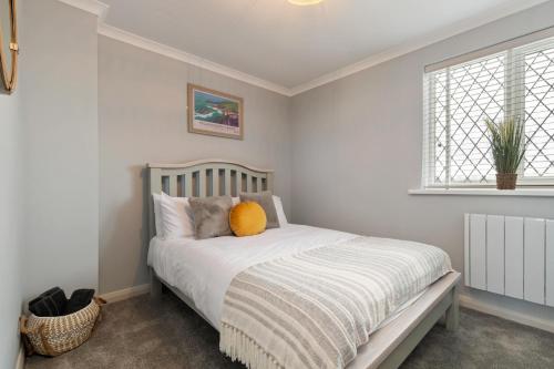 a bedroom with a bed with a orange pillow on it at Cartwright's Cottage - Indoor Pool, Sports Courts, Play Park in Saint Florence