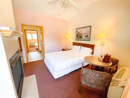 a bedroom with a bed and a table and a tv at Lake Bluff Inn and Suites in South Haven