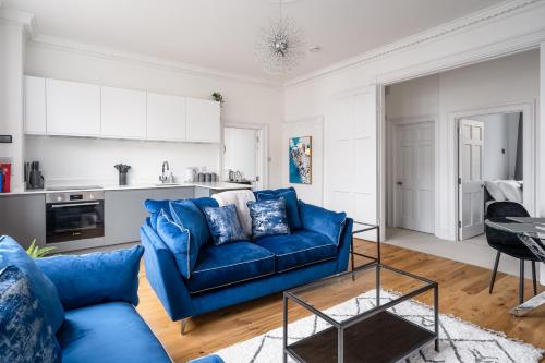 a living room with a blue couch and a kitchen at River Street View in Bath