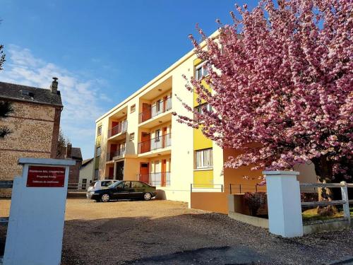 a flowering tree in front of a building with a car at Appartement rénové lumineux proche centre ville in Louviers