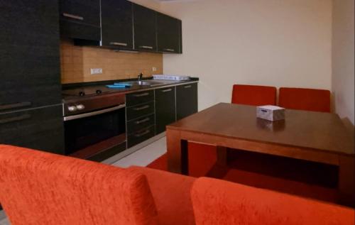 a kitchen with an orange couch and a wooden table at "Красавиците тъмнокоси" Sunset Resort Pomorie in Pomorie