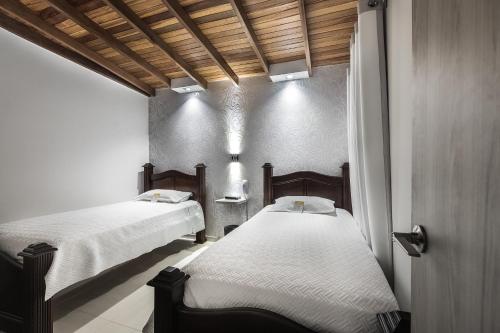 two beds in a room with white sheets at Casa Hotel Solare de la 70 in Medellín