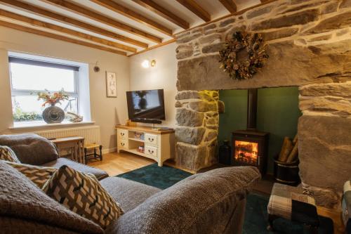 a living room with a stone fireplace and a tv at Cosy, coastal cottage in Snowdonia in Harlech