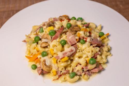 a white plate of pasta with meat and vegetables at Riivana Tavern in Lekki