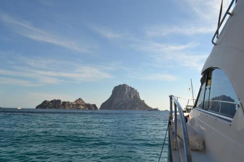 a boat in the water with cliffs in the background at Hotel Marfil in San Antonio