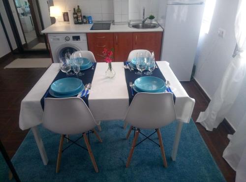 una cocina con mesa con 3 sillas, platos y copas de vino en Céntrico apartamento de dos dormitorios, amplio y luminoso en Plasencia