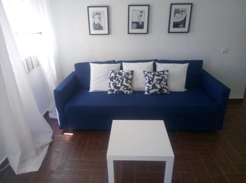 un sofá azul con almohadas y una mesa en la sala de estar. en Céntrico apartamento de dos dormitorios, amplio y luminoso en Plasencia