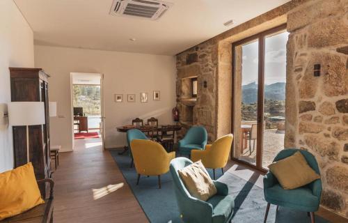 a living room with chairs and a stone wall at Quinta da Moita Agroturismo in Tabuaço