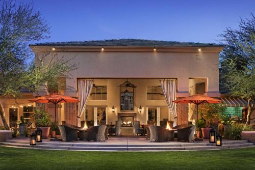 a building with a patio with umbrellas in front of it at Sonesta Suites Scottsdale Gainey Ranch in Scottsdale