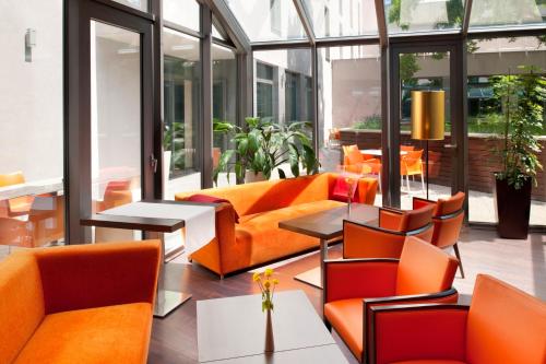 an office lobby with orange chairs and tables at Holiday Inn Trnava by IHG in Trnava