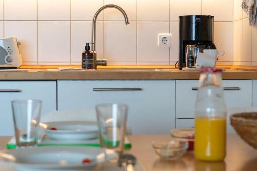 eine Küche mit einem Tisch mit Gläsern und einer Flasche Orangensaft in der Unterkunft "Ostseeresidenz", Wohnung 53 in Heiligenhafen