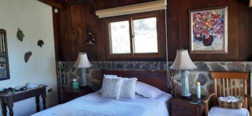 1 dormitorio con 1 cama, 2 lámparas y ventana en Casa BuenAventura - Cozy country cottage with wooden ceilings and stone walls within nature reserve en Panajachel