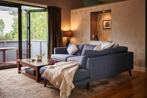 a living room with a blue couch and a table at Parehua Resort in Martinborough