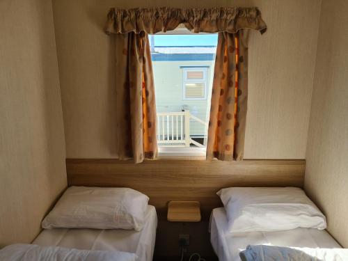 zwei Einzelbetten in einem Zimmer mit Fenster in der Unterkunft 8 Berth The Chase Ingoldmells (Horizon) in Ingoldmells