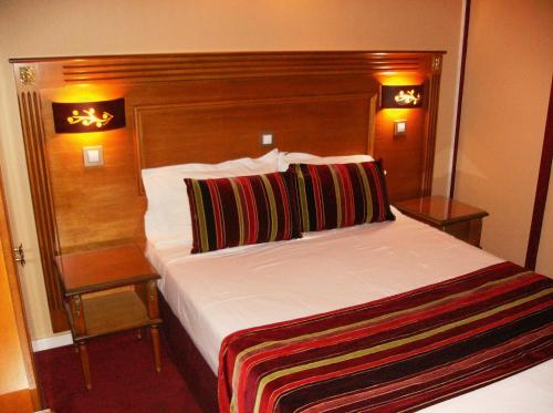 a bedroom with a large bed with a wooden headboard at Hôtel du Val de Seine in Mantes-la-Jolie