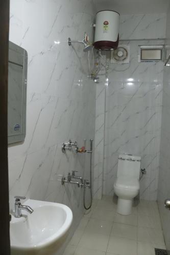 a white bathroom with a toilet and a sink at THE HOTEL MILLENNIUM in Imphal