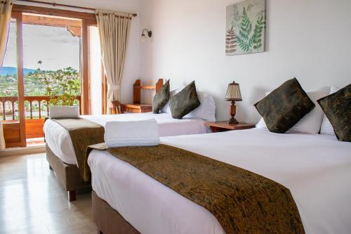 a hotel room with two beds and a window at Hotel El Giro in Villa de Leyva