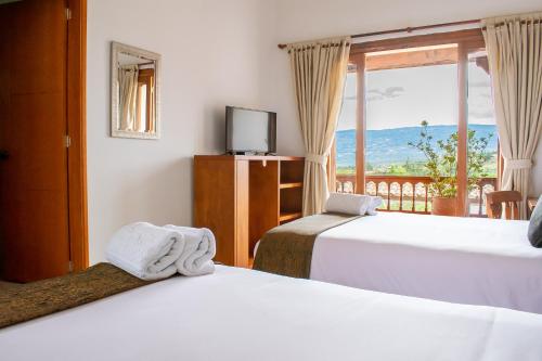a hotel room with two beds and a window at Hotel El Giro in Villa de Leyva