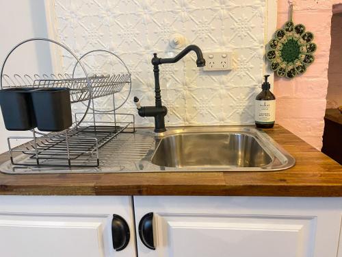 a kitchen sink with a faucet and a bottle of wine at Blue Duck Cottage Village Comfort with Fireplace in Tenterfield