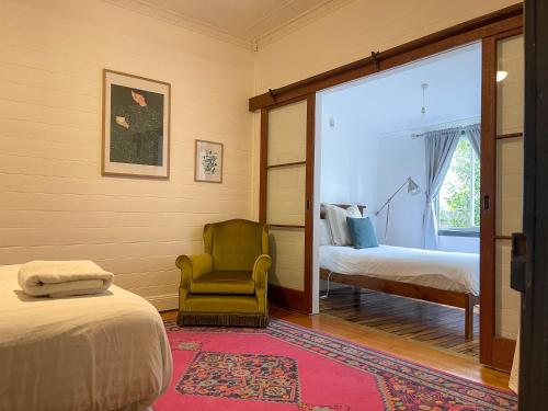 een slaapkamer met een bed, een stoel en een raam bij Blue Duck Cottage Village Comfort with Fireplace in Tenterfield