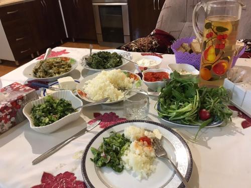 een tafel met borden en kommen groenten bij Guest House SAMAN in Garni
