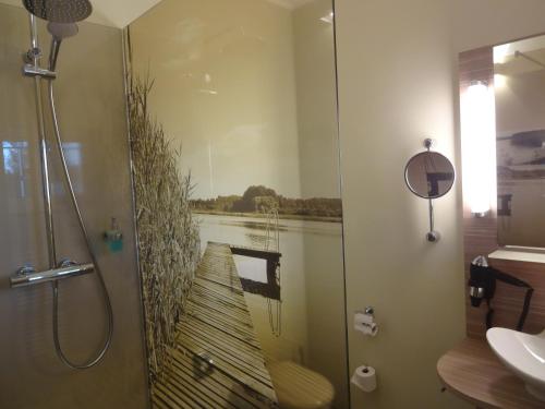 a bathroom with a shower with a painting of a canoe at Hotel am Untersee in Bantikow