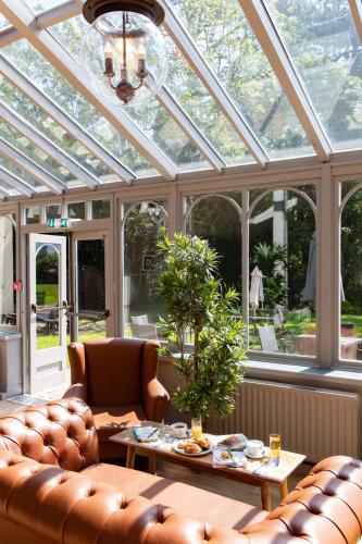 a conservatory with a glass roof with a couch and a table at The Derwentwater Hotel in Keswick