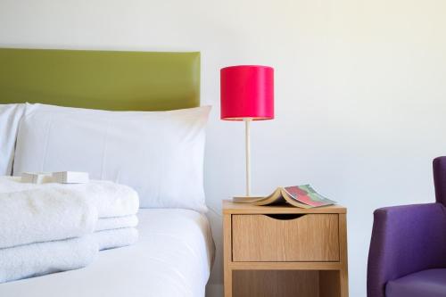 a bedroom with a bed with a red lamp and a chair at The Derwentwater Hotel in Keswick
