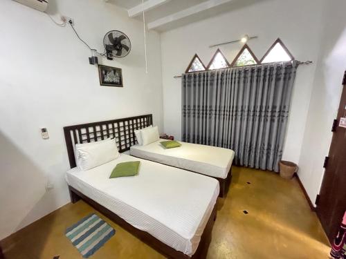 two beds in a room with a window at Hotel Gala Addara in Dambulla