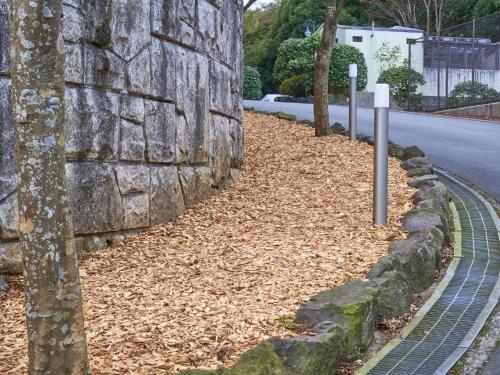a stone wall with leaves on the side of a road at Hotel Village Izukogen in Ito