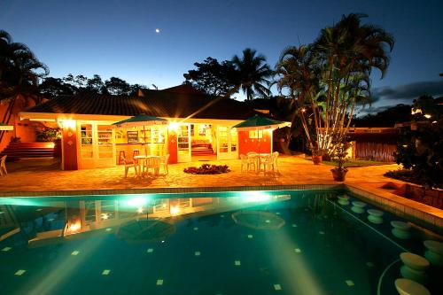 a swimming pool in front of a house at night at Hotel Ilhasol in Ilhabela