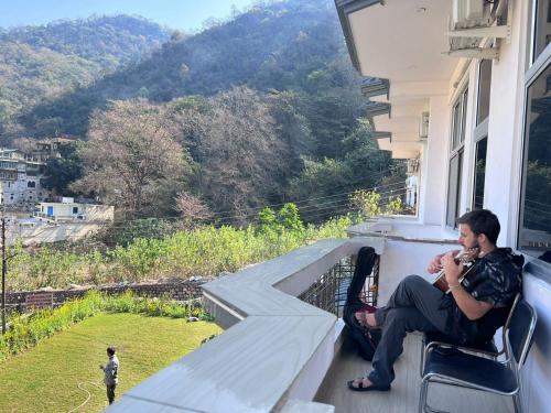 a man sitting on a porch talking on a cell phone at Hotel Manikut in Rishīkesh