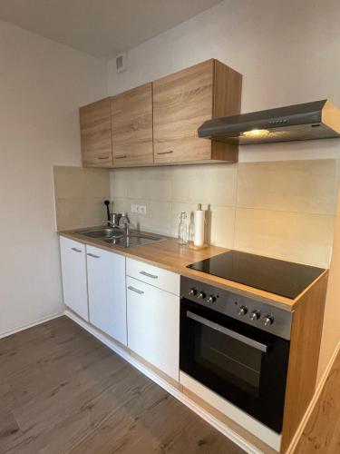 een keuken met witte kasten en een zwarte oven bij Central Cosy Apartment in Cologne in Keulen