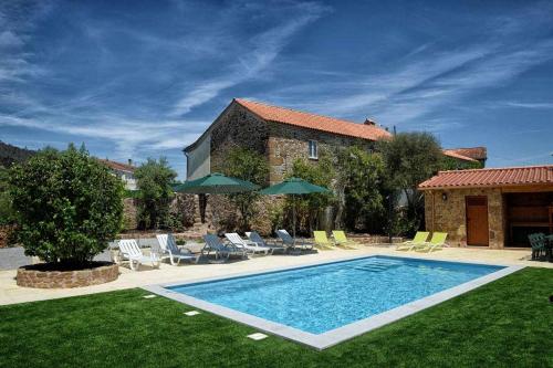 - une piscine dans une cour avec des chaises et des parasols dans l'établissement Casa do Tanque Camélias de Basto, à Castelbuono