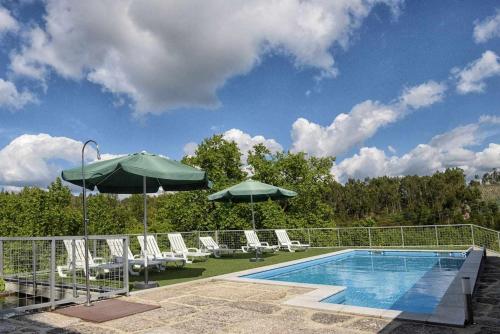 a swimming pool with lounge chairs and umbrellas next to a swimming pool at Casa de Barreiros (Camélias de Basto) in Lamelas