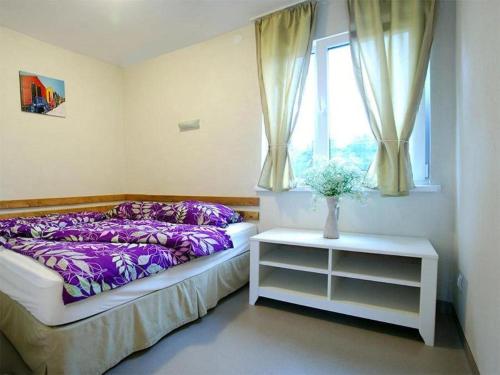 - une chambre avec un lit doté de draps violets et une fenêtre dans l'établissement Beluga, à Šventoji