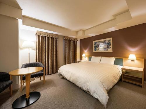 um quarto de hotel com uma cama e uma mesa e cadeira em Utsunomiya Tobu Hotel Grande em Utsunomiya