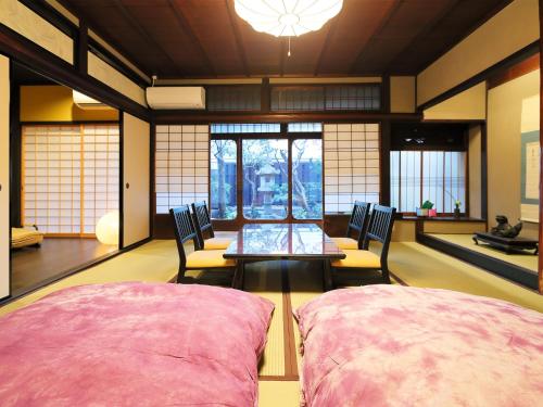 Zimmer mit 2 Stühlen, einem Tisch und Fenstern in der Unterkunft Ryokan Tanoya in Kyoto