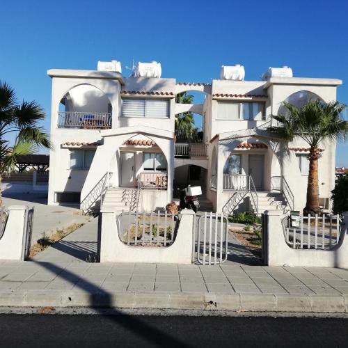 a large white house with palm trees in front of it at Lovely 1betroom apartment near the beach in Pyla