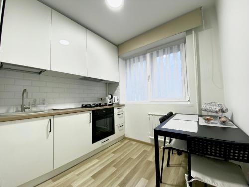 une cuisine avec des placards blancs et une table noire dans l'établissement Stay in Kaunas! Brand new, 2 rooms, à Kaunas